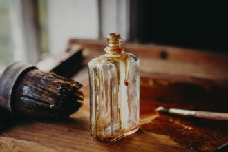 Glass bottle and brush on a wooden table with dried varnish