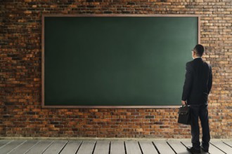 Geschäftsmann schauen und denken vor einer Ziegelwand mit leeren Kreideboard