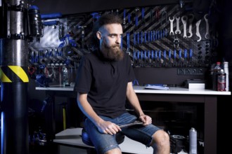Portrait of small business owner of young man with beard. Guy bicycle mechanic workshop worker