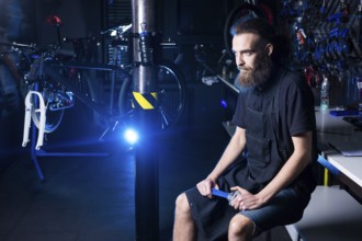 Portrait of small business owner of young man with beard. Guy bicycle mechanic workshop worker
