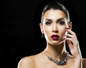 Romantic woman with dramatic makeup and nailpolish. Big blue silver fashion necklace. Black