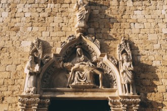 Facade of the Franciscan monastery with high relief depicting holy images in the old town of