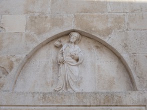 Stone relief on church façade, figure of a saint, old town centre of Korcula, island of Korcula,