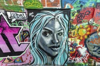 Street art, graffiti of a portrait of a woman by alleyway artists in the graffiti alley in