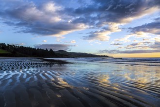 Strips of sand and water left by the ocean tide. Sunrise over the ocean. New Zealand, Pacific Coast