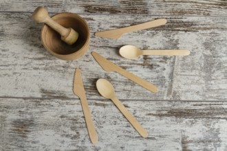 Wooden mortar with a pusher and other tools. Knives and spoons. Top view flat lay