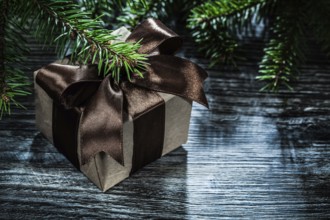 Gift box with ribbon pine branches on wooden board