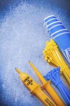 Yellow electrical tester self-locking cable ties blue construction plans on metallic background