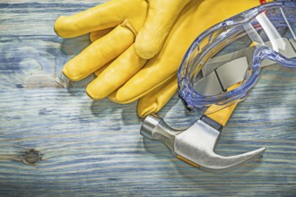 Protective glasses leather gloves claw hammer on wooden board construction concept