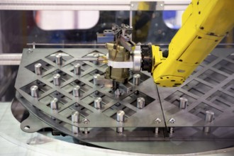 Yellow robotic arm arranges metal elements after being produced. Automatic industrial machinery