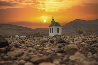 Small, sweet white wooden chapel in a barren volcanic landscape. Sunset, landscape shot of the