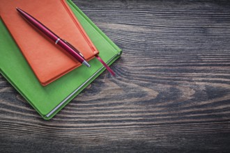 Closed diary books ballpoint pen on vintage wood board office concept