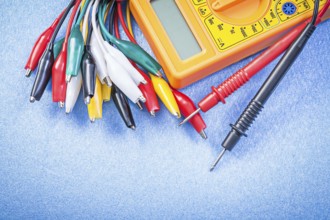 Crocodile plugs digital multimeter on blue background top view electricity concept