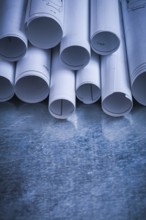 Pile of rolled engineering drawings on scratched silver-metal background building and architecture