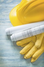 Hard hat construction plans protective gloves on wooden board building concept