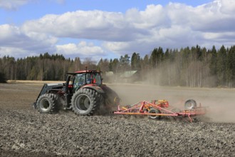 SALO, FINLAND, MAY 7, 2017: Farmer cultivates field with red Valtra tractor and Potila seedbed