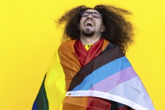 Happy smiling gay man wrapping with a rainbow lgbt flag