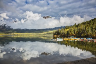 Pyramid Mountain reflected in Pyramid Lake. Wooden boat dock with moored pleasure boats and benches