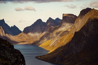 Dramatic view of a fjord with towering mountains casting shadows along the landscape, mountains,