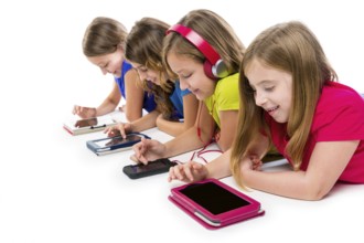 Sisters cousins kid girls with tech tablets and smatphones in a row lying on white background
