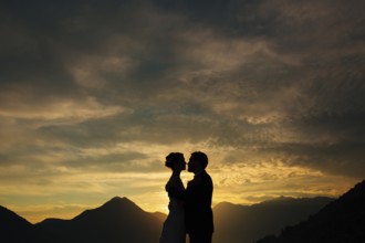 Silhouette of a newlywed couple on the background of the setting sun on the sea in Montenegro
