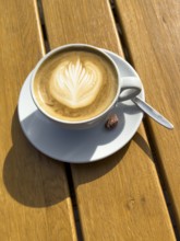 Coffee drink Cappuccino Cappuccio with flower pattern in milk foam, next to it single roasted