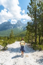Woman hikers walking on Valbona Valley trail next to trees, Theth National Park, Albanian Alps,