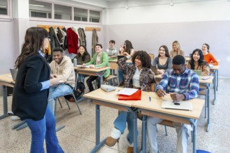 Multi ethnic university students attending a lesson with their professor, participating actively