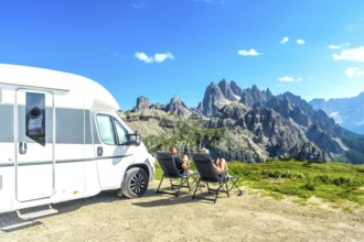 Family relaxing in camping chairs, enjoying breathtaking view of tre cime di lavaredo, dolomites,