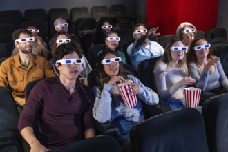 People of diverse ages wearing 3d glasses, eating popcorn, and watching a movie in a cinema,