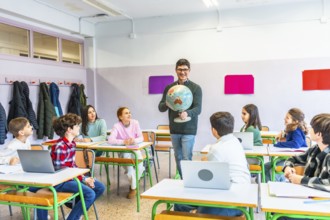 Geography teacher engaging students while holding a globe, fostering learning and understanding in