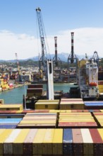 High angle view of stacked rectangular metal box shipping containers and gantry cranes on dock in