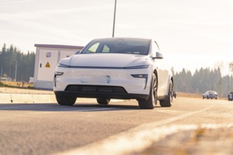 Modern white car on an asphalt road with natural landscape in the background, Tesla, New Model Y