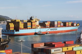 Maersk Serangoon cargo ship loaded with metal box shipping containers being guided by pilot boats