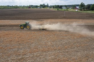 Hudson, Michigan, A cloud of dust blows behind the tractor as a farmer tills his field