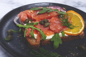Sandwich with freshly smoked salmon, on black bread, with cottage cheese, with herbs and red