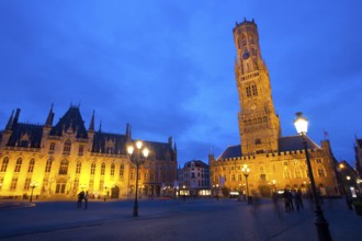 The provincial courthouse and belfry are illuminated at dusk in grote markt, the city center of