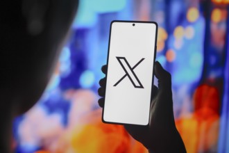 In this photo illustration, the X (Twitter) logo is displayed on a smartphone screen