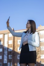 Business, middle-aged, brown-haired woman in a white shirt, black skirt and blue jacket is making