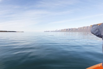 Greenlandic man hunting for seal in Greenland, pointing the gun towards the water, Greenland, North