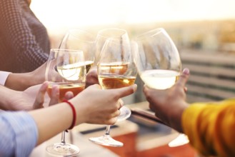Group of anonymous people clinking wineglasses and proposing toast during party on rooftop