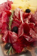 Assorted meat, appetizer, prosciutto, salami and ham, with maasdam cheese and olives, on a wooden