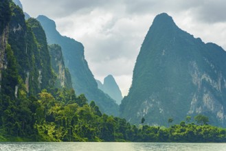 Misty mountain peaks covered in dense greenery under a cloudy sky, Cheow Lan Lake, Khao Sok