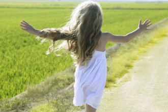 Rear view running open arms little happy girl green meadow field track