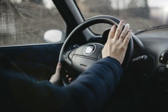 Person places hand on wheel as if to use the horn inside an overcast vehicle
