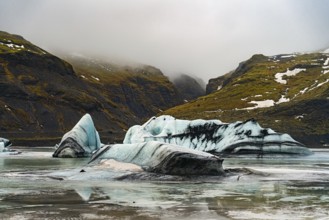 Layers of icebergs against a backdrop of towering mist-covered mountains, iceberg Iceland, glacier,