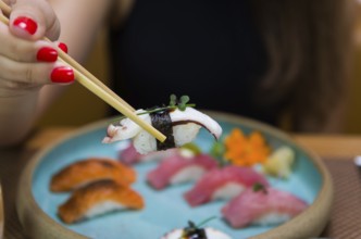 Woman eating delicious sushi, closeup on chopsticks