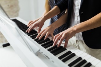 Close up couple s hand playing piano keyboard