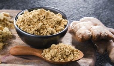 A bowl with ground ginger and its fresh rhizome