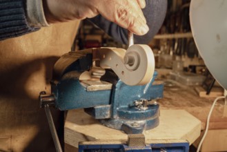 Italian luthier is meticulously shaping the scroll of a violin using a gouge, with the piece